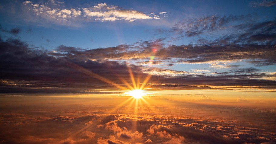 beautiful sunrise breaking through blue sky over cloud horizon