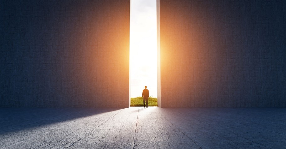 Businessman walking to open big gate to a bright outside world