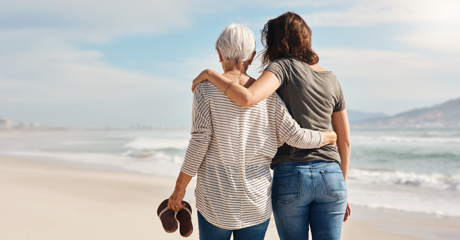 Mom with adult daughter walking on the beach.