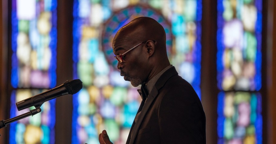 Man preaching in front of a stain-glass window