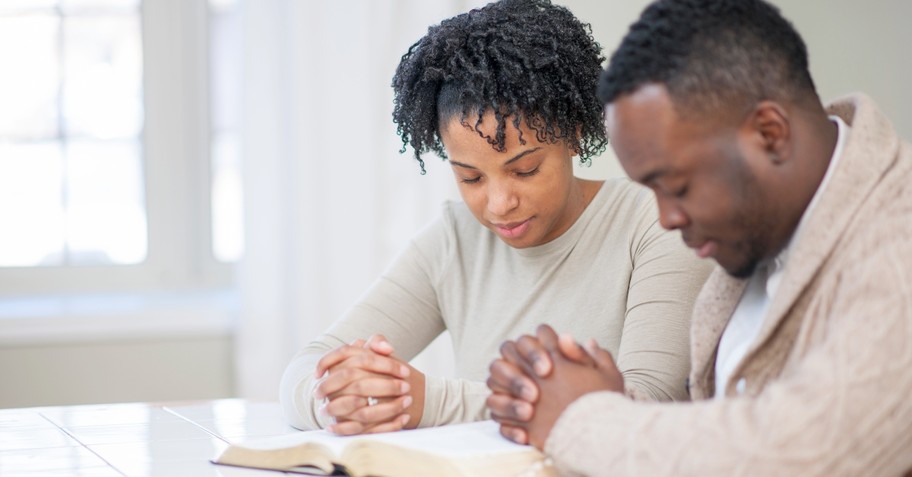 A couple praying over the Bible