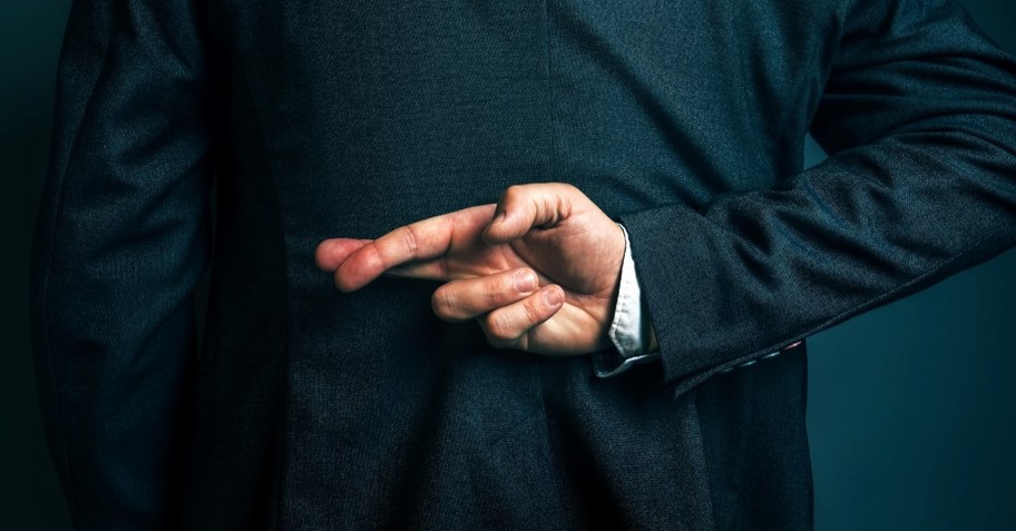 man with fingers crossed, lying