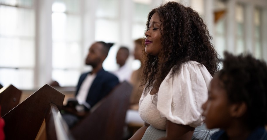 Mom and son sitting at church pew praying