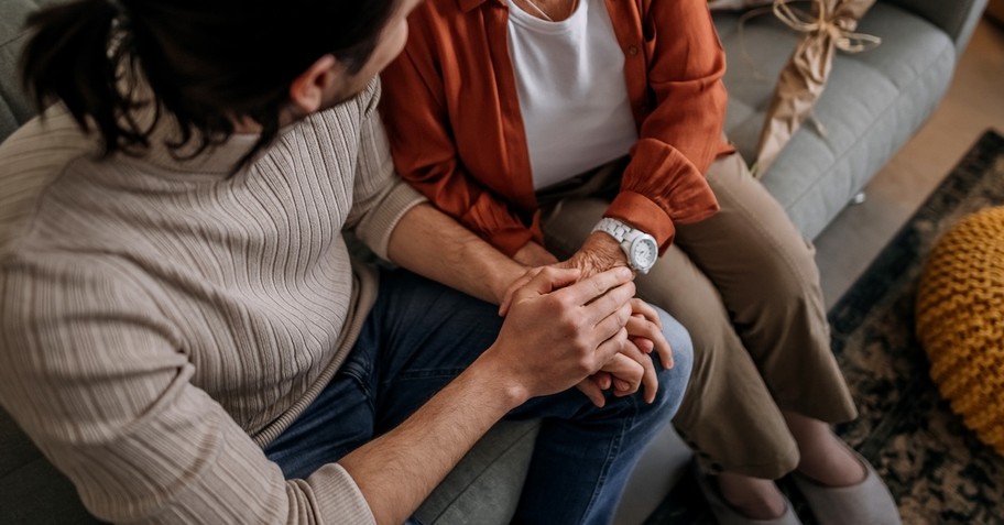 Adult son and mom talking on couch apologizing forgiving reconciliation