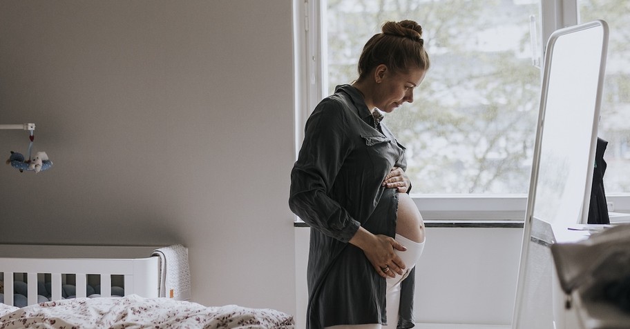 Pregnant mom looking in mirror belly
