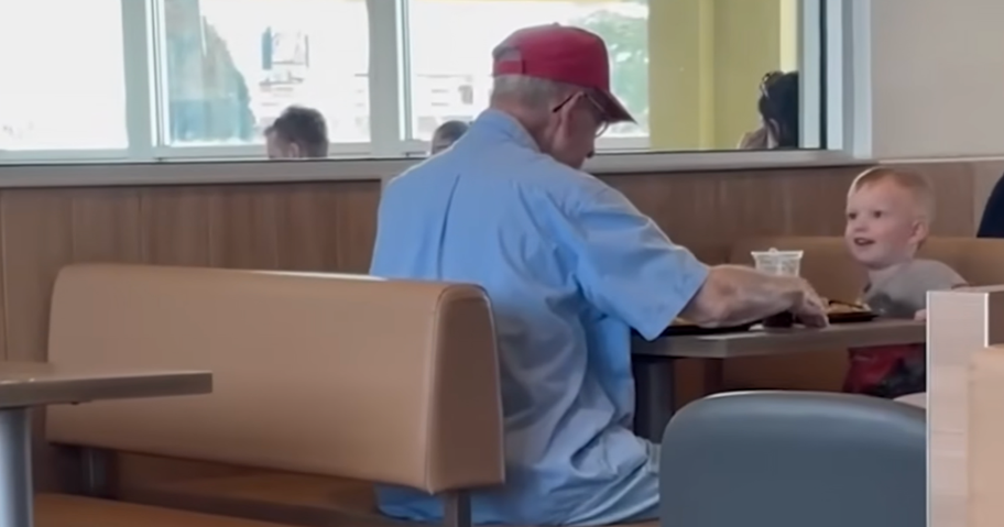 a toddler sitting with an elderly man in a McDonald's booth