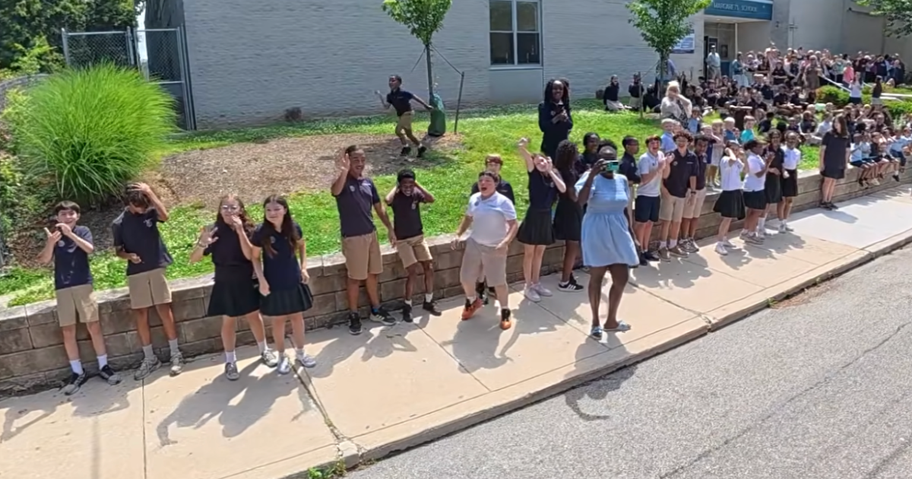 students outside of school waving