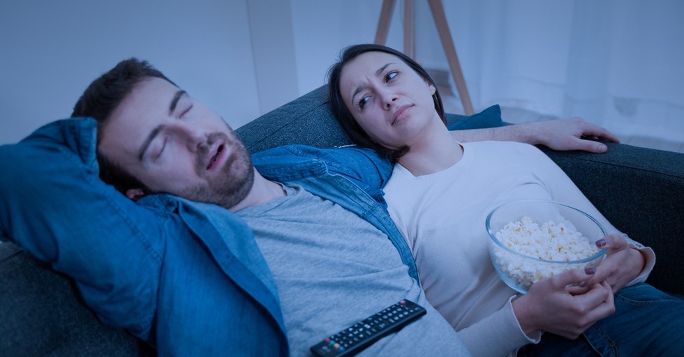 couple sitting on couch with popcorn watching movie looking tired and annoyed, keep marriage alive under lockdown
