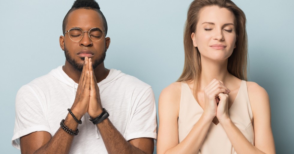 man and woman standing in prayer eyes closed