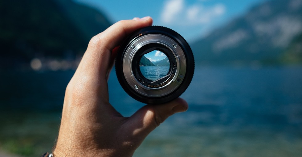 hand holding up camera lens to view of mountain lake, prayer for finding life purpose