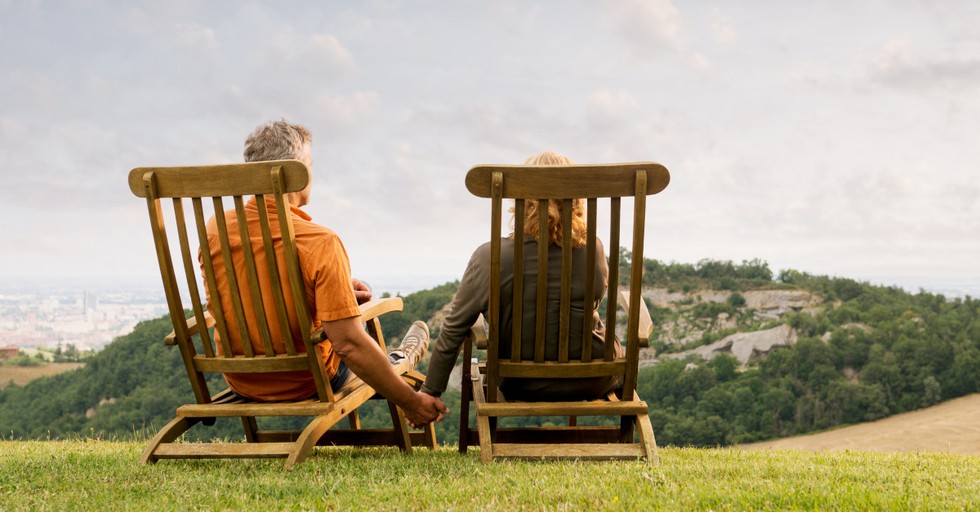 senior couple on scenic mountain overlook holding hands in deck chairs