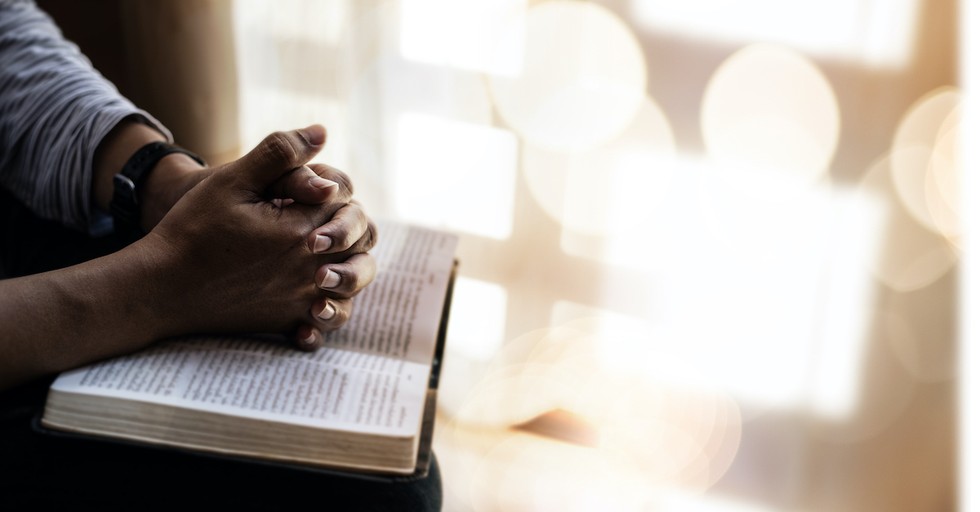 man resting hands on open Bible