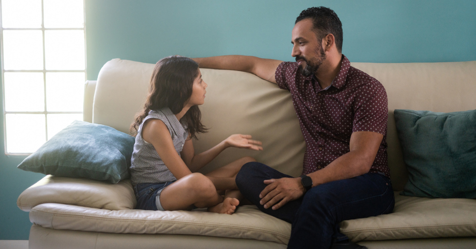 Father and daughter sitting on a couch talking; 4 important lessons on fatherhood.