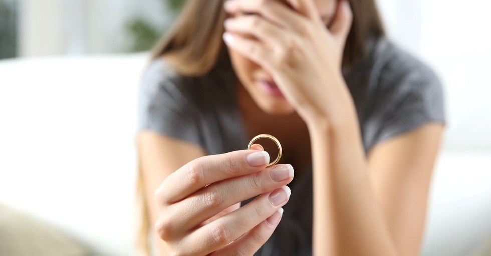 crying woman holding wedding ring